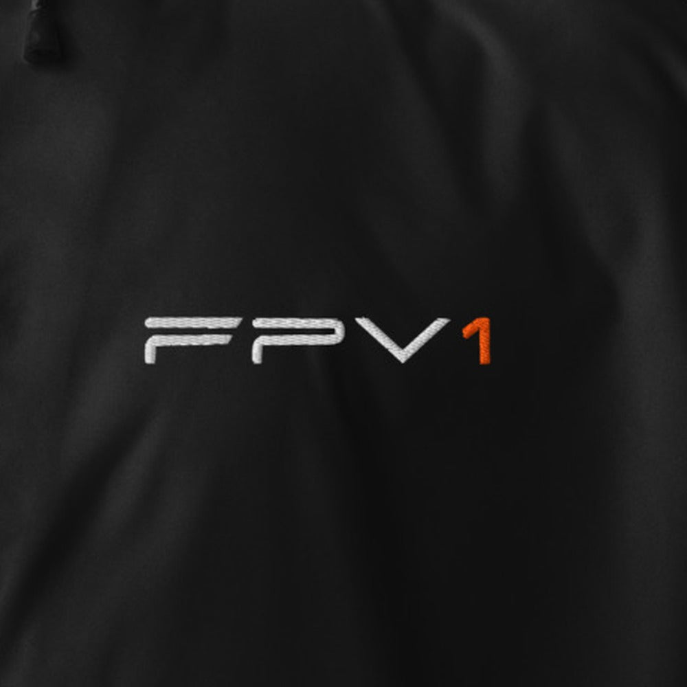 FPV1 Embroidered Windbreaker in Black – close-up of the embroidered chest wordmark